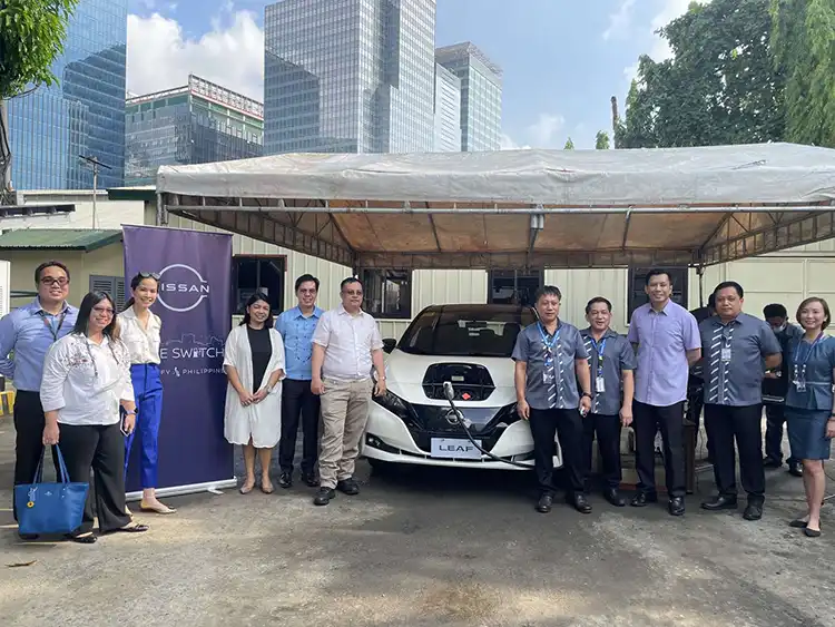 A group of people standing with the Nissan Leaf