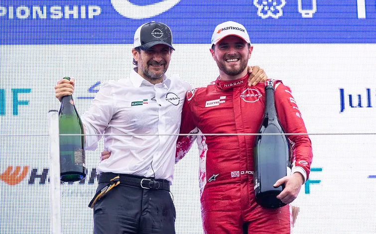 東京E-PRIX 2025 2日目に電撃的な勝利を果たし、一緒に表彰台に上がった日産フォーミュラEチームのマネージングディレクター兼チーム代表のトマソ ボルペと23号車ドライバーのオリバー ローランド。両者とも大きなシャンパンボトルを持っている。