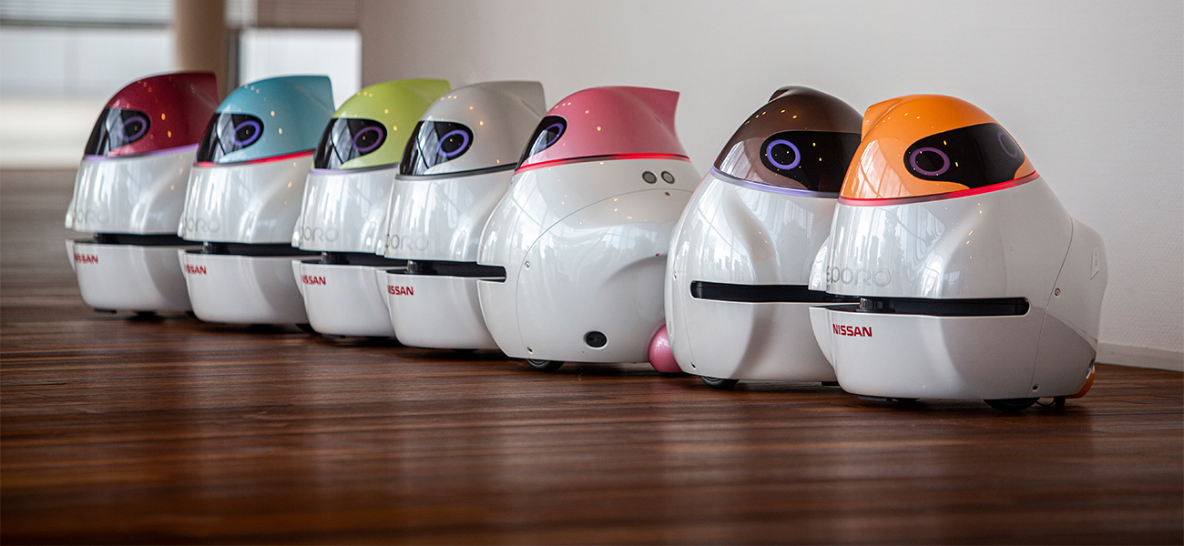 7 robots in a line on wood floor.