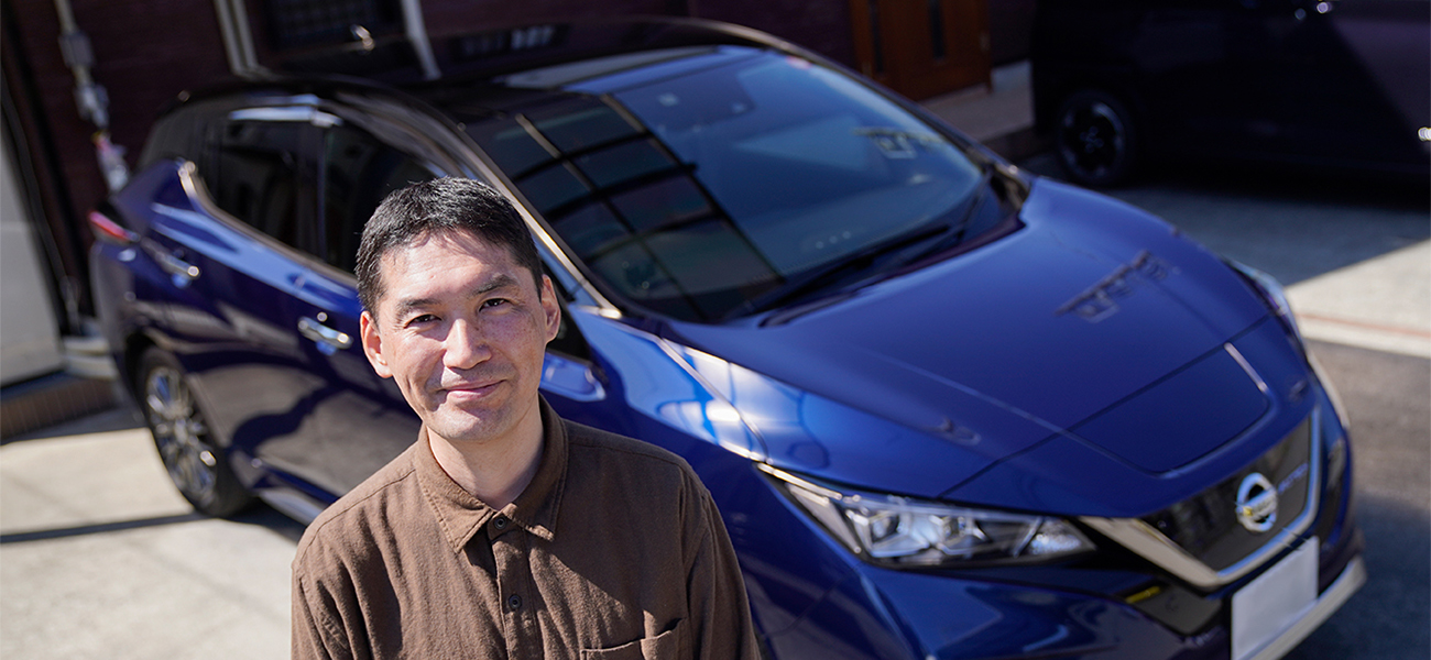 Man smiling and looking up next to blue vehicle