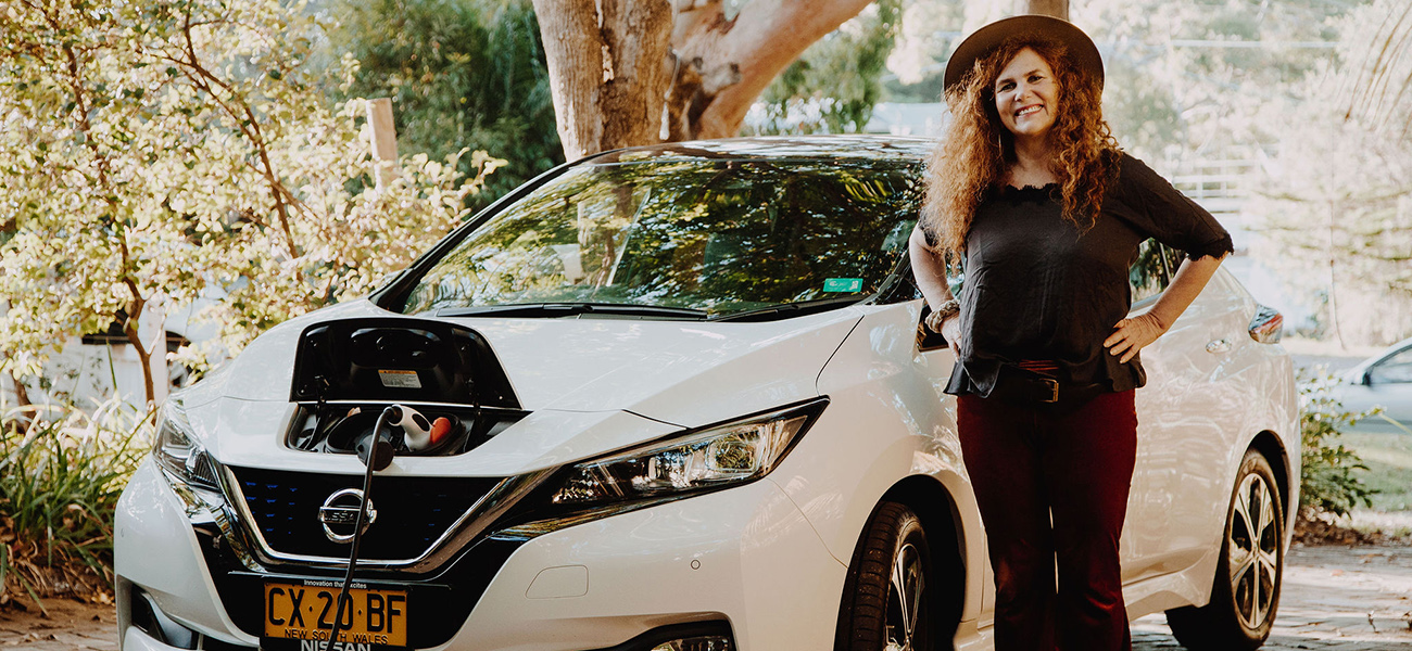 Natalie Isaacs standing in front of a white Nissan LEAF EV.