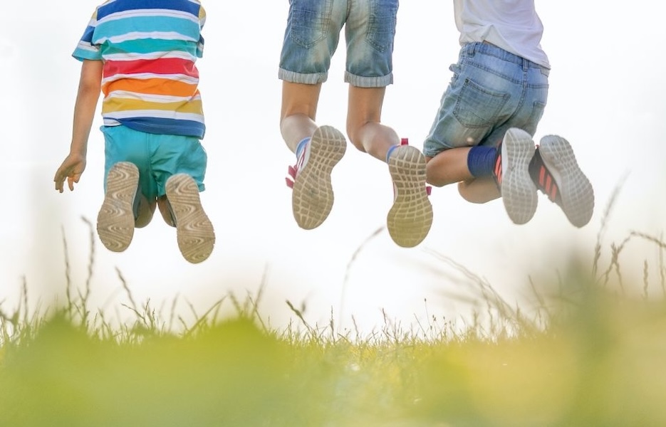 children jumping midair on a grassy field