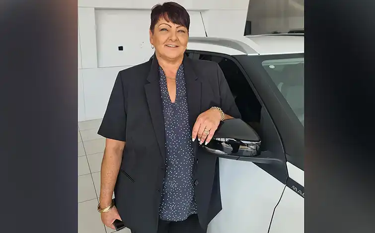 Isobel Lamprecht posing for a photo while resting her arm on the side mirror on a Nissan