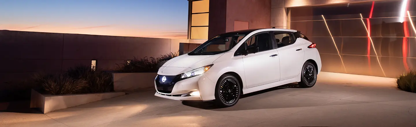 Nissan LEAF 2023 garée devant un garage la nuit