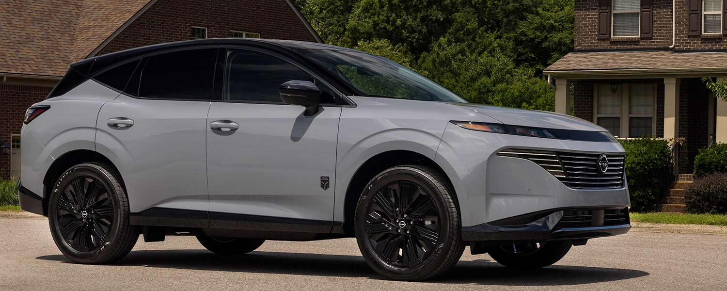 Front right 3/4 view of the 2027 Nissan Murano Dark Armor parked in front of a house.