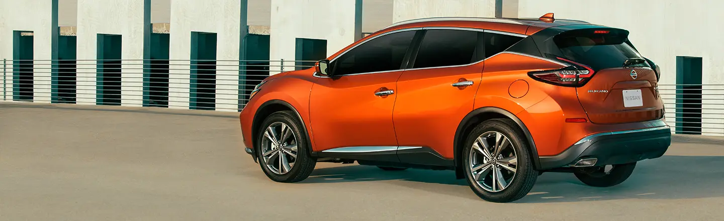 Rear driver side picture of a Red Nissan Murano atop parking structure
