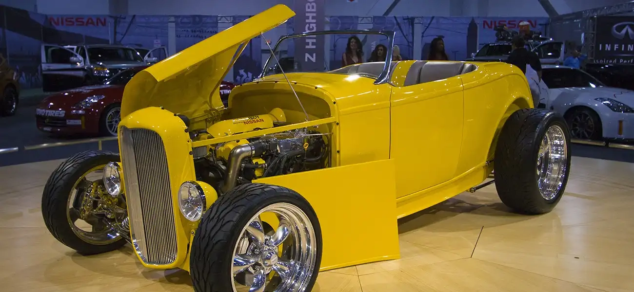 A yellow Z Highboy Roadster parked on a wooden stage.