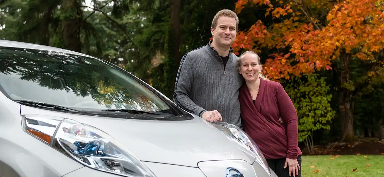 A couple pausing with their silver Nissan LEAF.