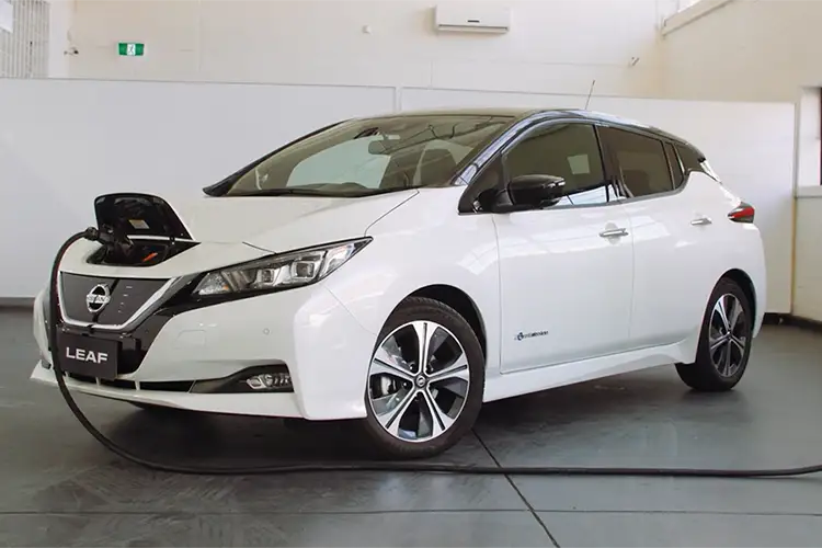 A white Nissan Leaf parked at a charging station