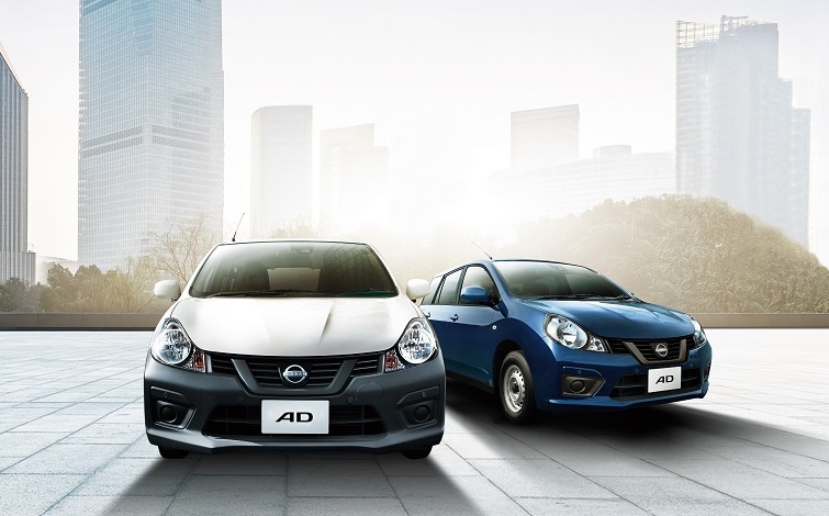 遠景に高層ビルが立ち並ぶ広場に正面向きで停車する日産AD2台（左：VEホワイト、右：エクセレントブルー）
