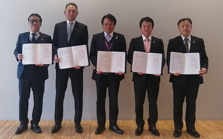 協定締結式で、協定書を手に持って記念撮影する各代表者