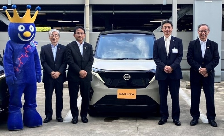 電気自動車の前で記念撮影する各代表者