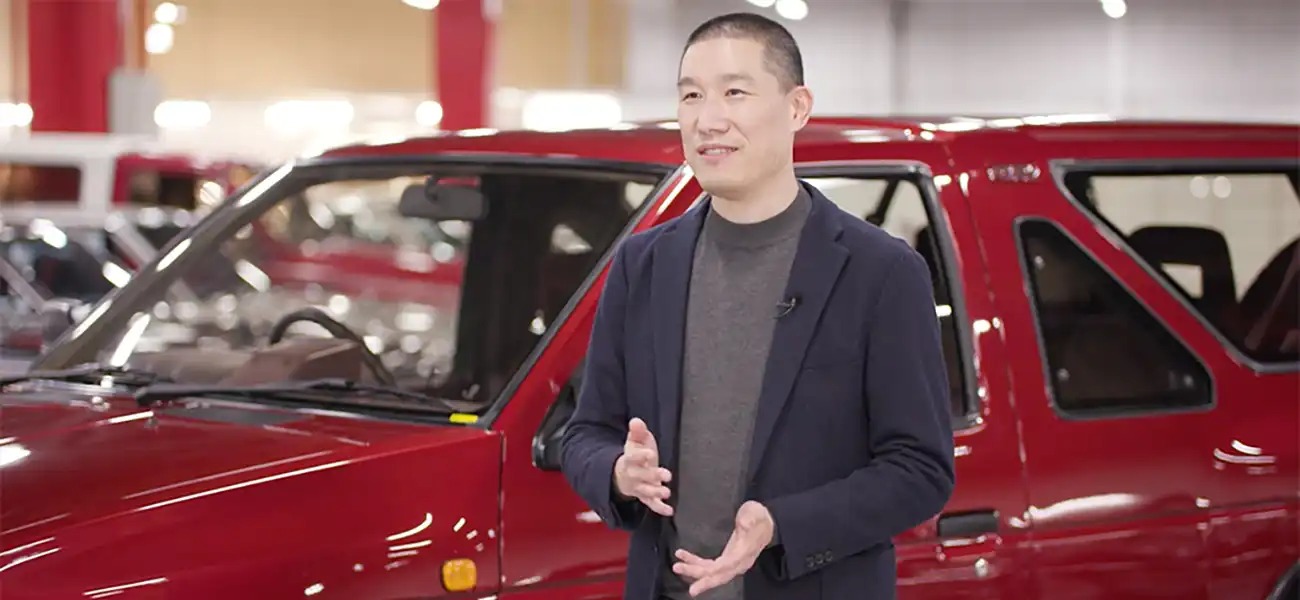 Ken Lee standing in front of a red Nissan vehicle.