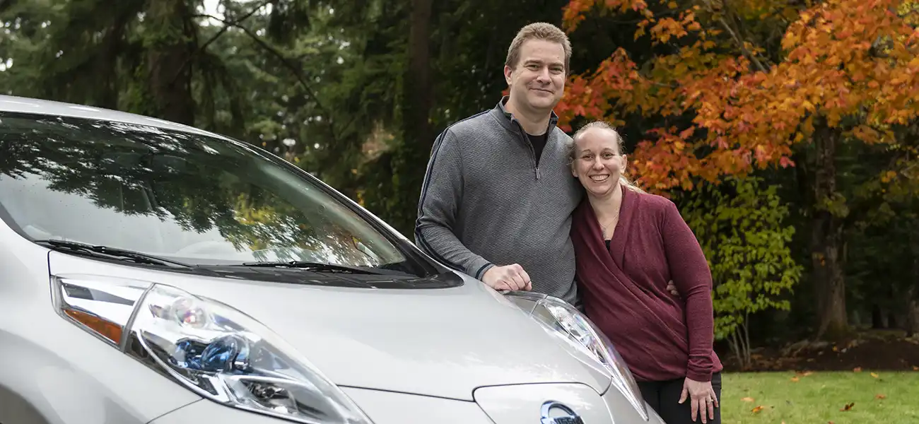 A couple pausing with their silver Nissan LEAF.