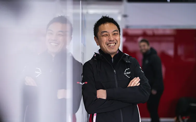 Tadashi Nishikawa, Chief Powertrain Engineer at Nissan Motorsports, leaning on a wall