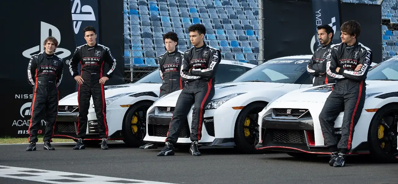 Gran turismo drivers in black, white and red racing suits leaning on white racing GT-Rs on a racetrack.