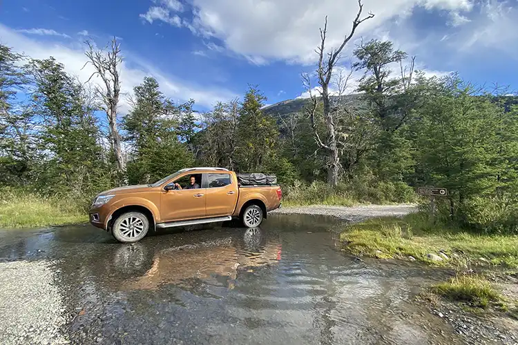Una Nissan Frontier de cobre en un río poco profundo.