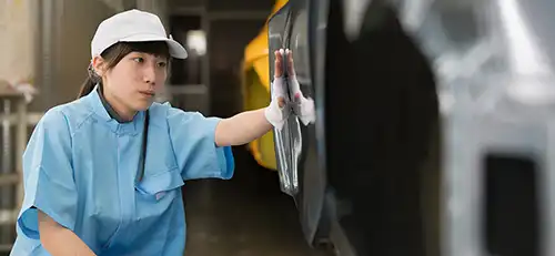 Employee touching side of vehicle in factory