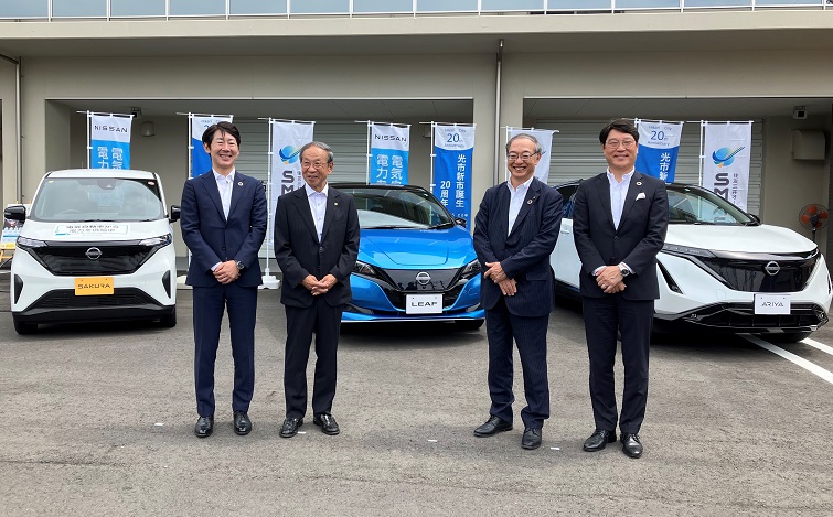 電気自動車の前で記念撮影する各代表者