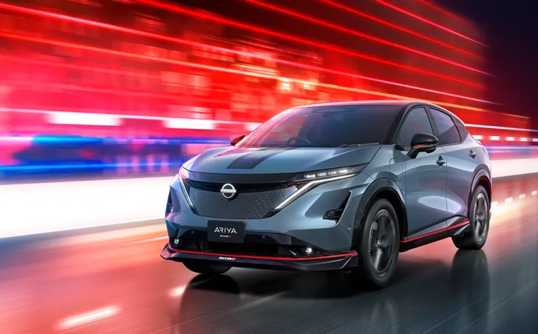 赤い光のラインを背景に、日産アリアNISMOが道路を疾走する姿