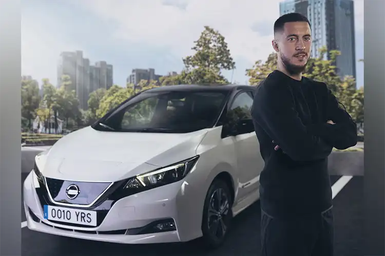 Un hombre se detiene frente a un Nissan LEAF blanco.