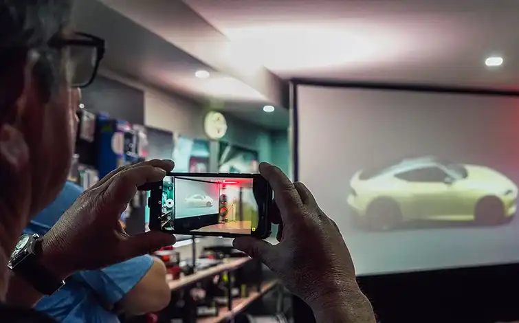 Man takes photo of a projected image of a Nissan Z