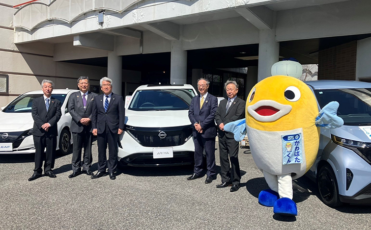 電気自動車の前で記念撮影する各代表者