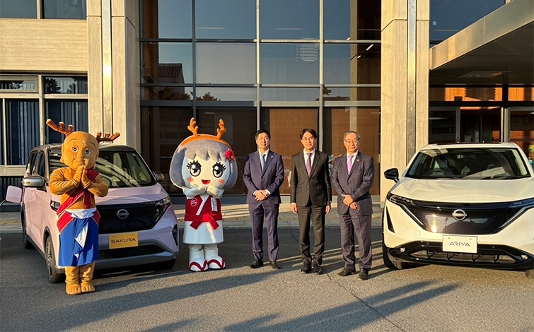 電気自動車の前で記念撮影をする各団体代表者
