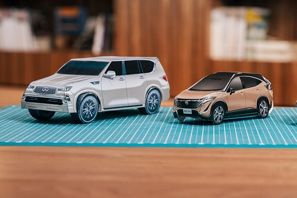 3 paper cars on a wooden table.