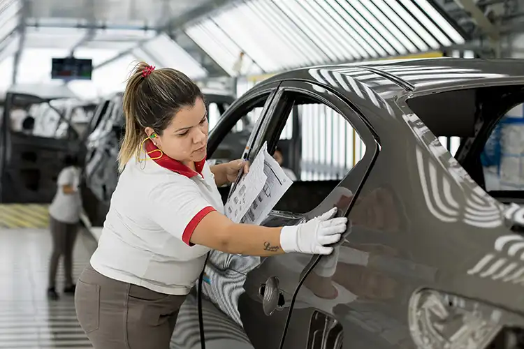 Uma pessoa inspecionando um carro na linha de produção