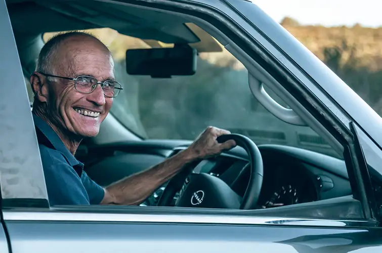Doug Sprigg poses for a photo in the driver seat of his car