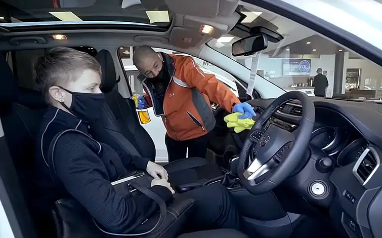 Nissan employee disinfecting the inside of a car.