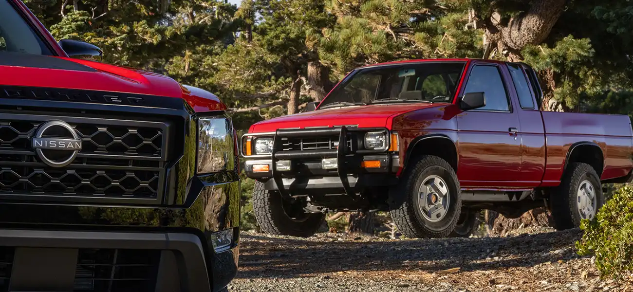 A red hardbody parked in the woods.