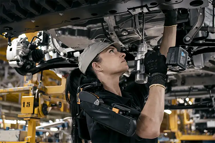 Una persona que trabaja en un automóvil asistida por un equipo.