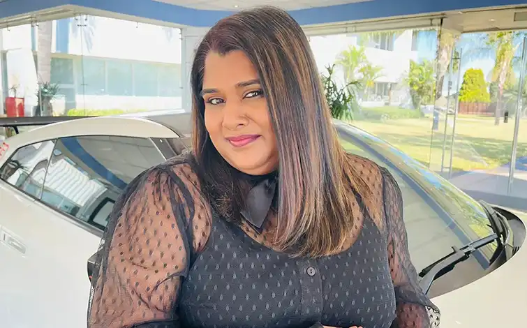 Natasha Naidoo posing in front of a Nissan Vehicle