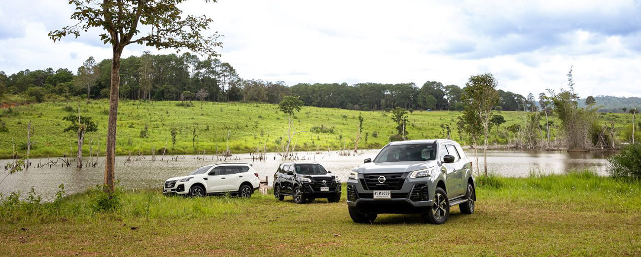Vehicles parked in grassy area near water
