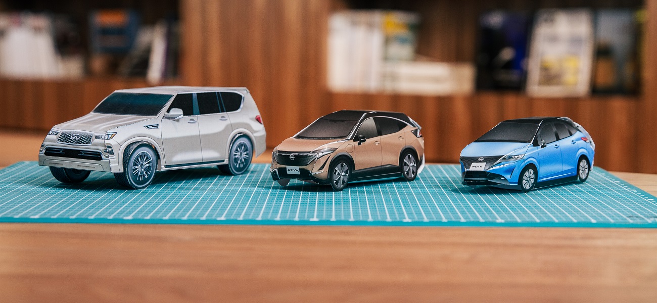 A photo of 3 paper Nissan cars on a table mat.