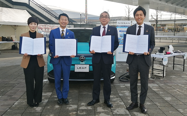 電気自動車の前で記念撮影をする各団体代表者