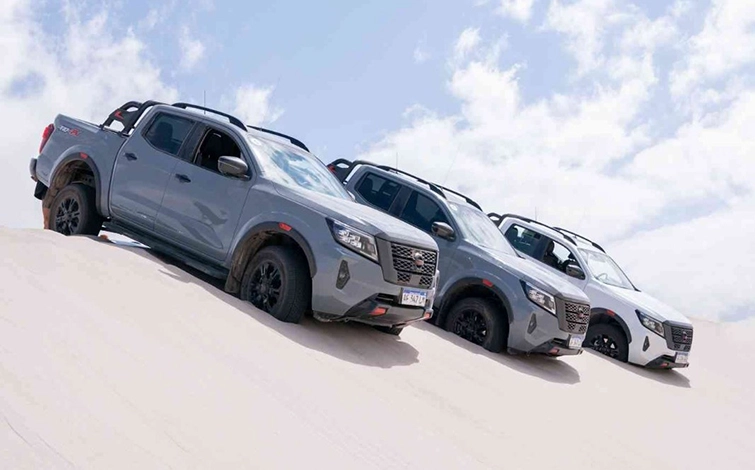 3 camionetas en diferentes colores sobre arena