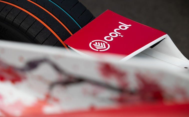 A white version of the Coral logo on a red background pictured on the Nissan Formula E Team race car livery.