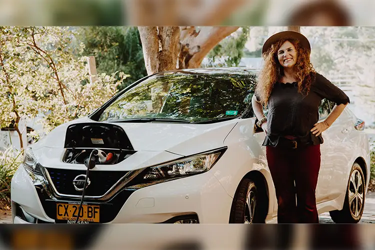 Natalie Isaacs standing in front of a white Nissan LEAF EV.