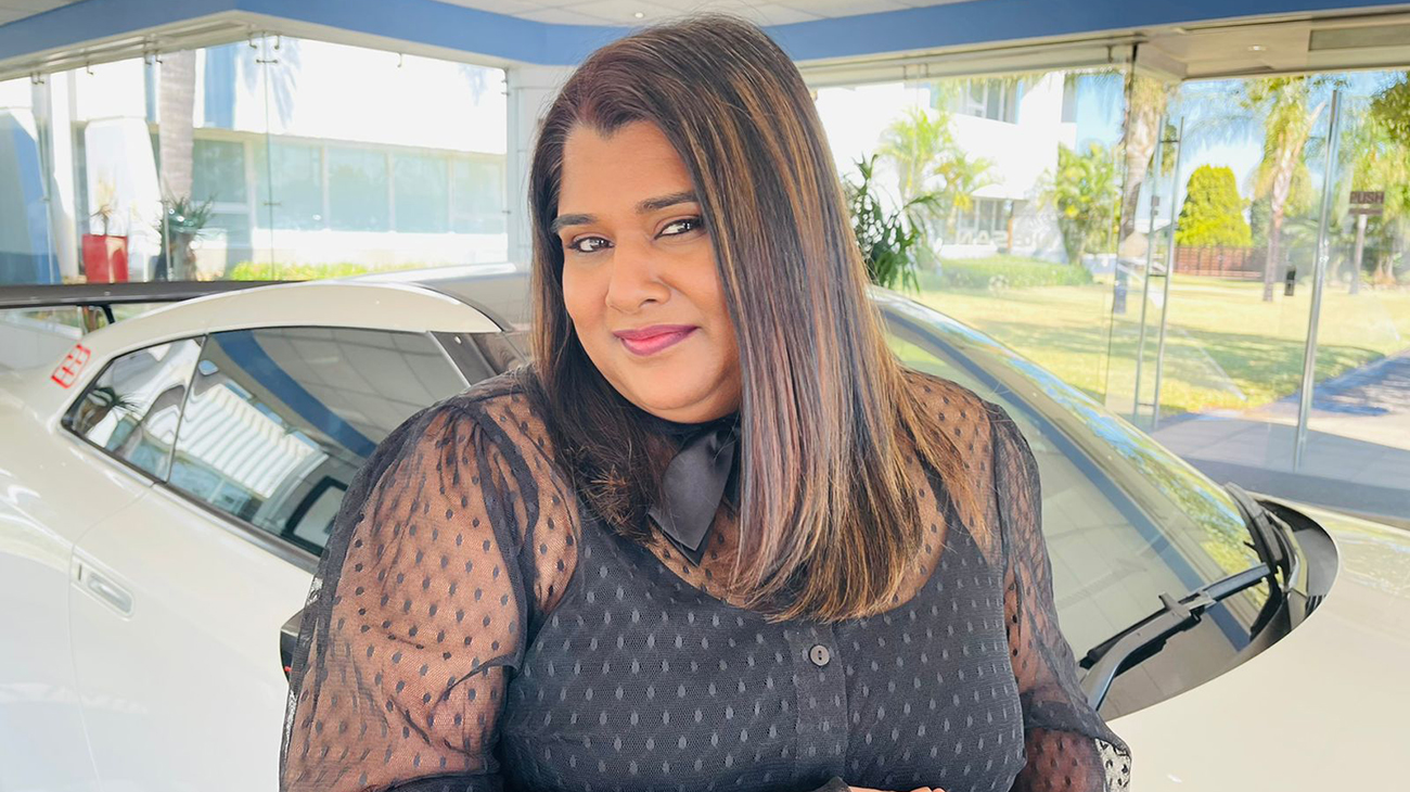 Natasha Naidoo posing in front of a Nissan Vehicle