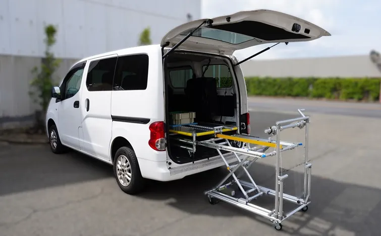 バン後方の地面上に配置された搬送台車。荷台が上昇し車両の荷室内まで伸びている状態。