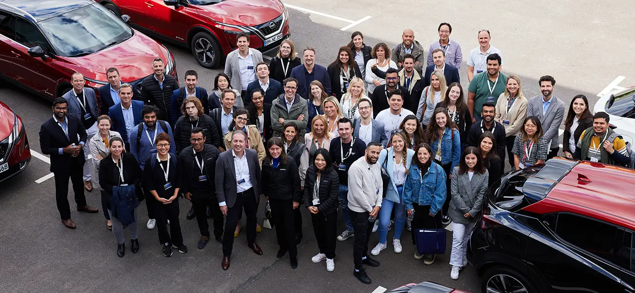 A group of people standing in a parking lot smiling for photo