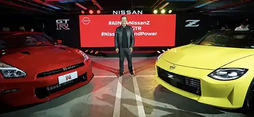 A person standing in front of Nissan GT-R Vibrant Red and The All-New Nissan Z Ikazuchi Yellow