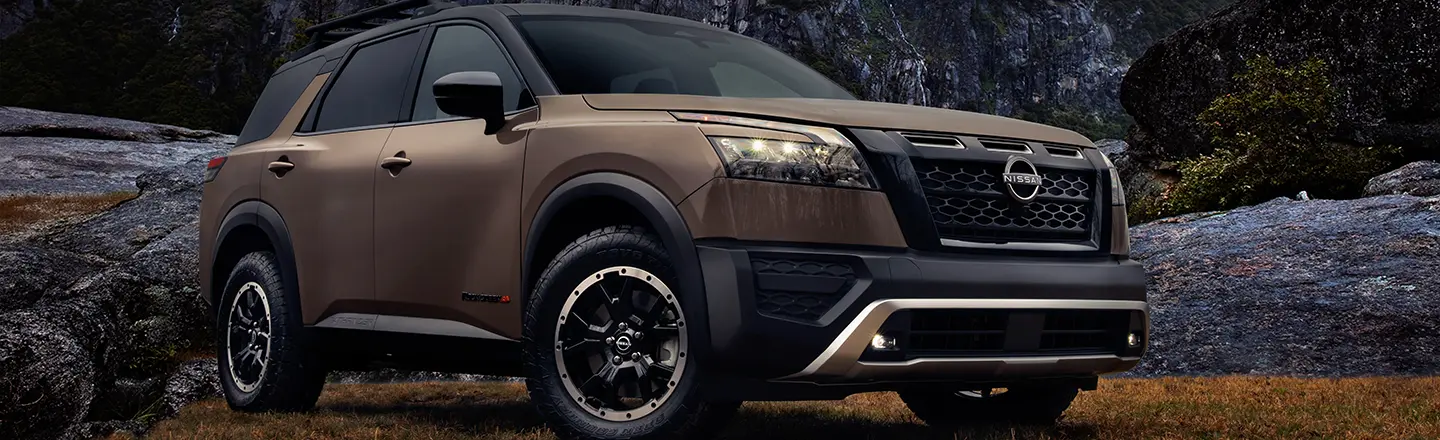 Front left 3/4 image of a Nissan Pathfinder with dark clouds and rocks behind