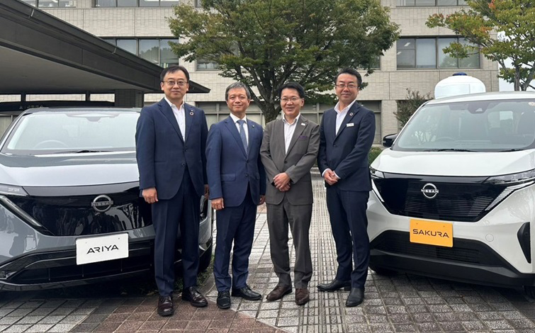 電気自動車の前で記念撮影をする、京田辺市、同支社大学、日産自動車の各団体代表者