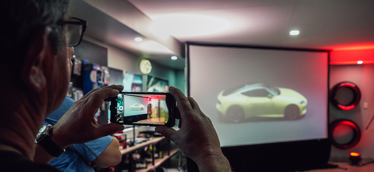 Man takes photo of a projected image of a Nissan Z
