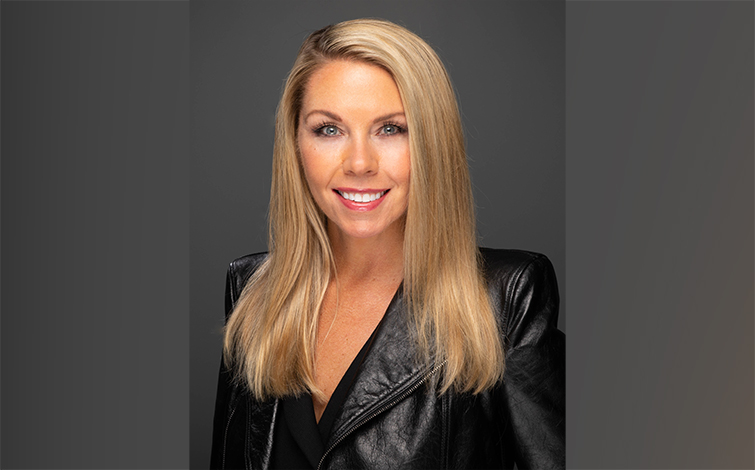 Allyson smiling brightly wearing a leather jacket against a gray background.