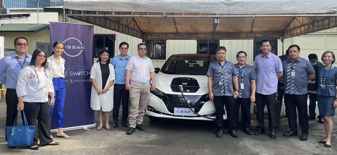 A group of people standing with the Nissan Leaf